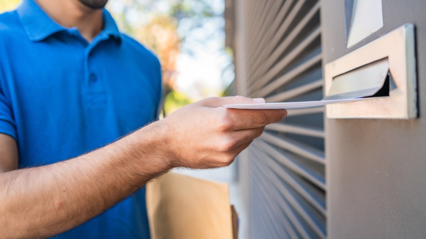 Postman putting letter in mailbox.