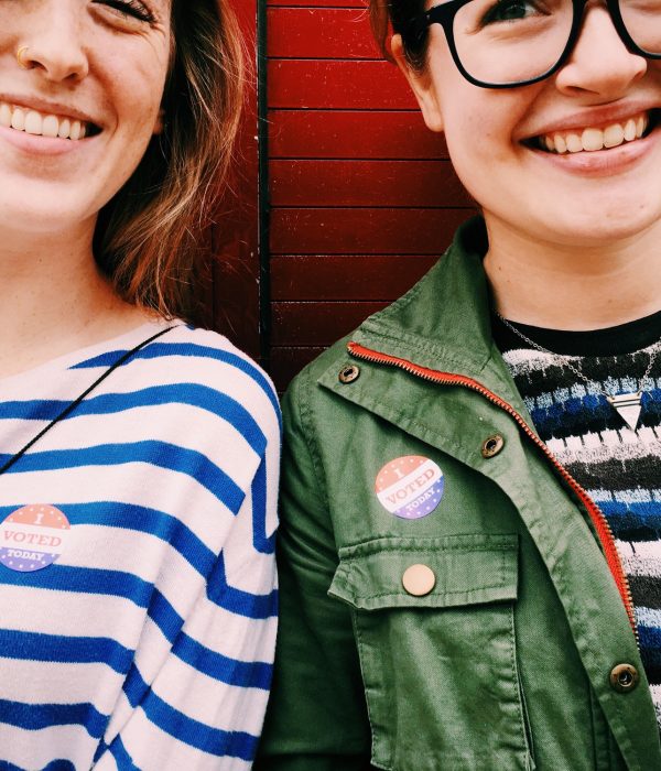 Two young woman wearing "I VOTED" stickers.